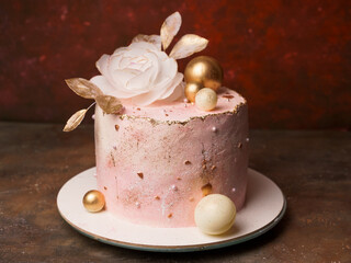 A trendy home-made pink cake decorated with a large flower and golden balls. Modern wafer paper cake decorations