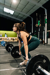 Fototapeta na wymiar Young fitness woman doing barbell squats in a gym