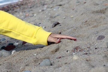 The girl's hand in yellow on the sand