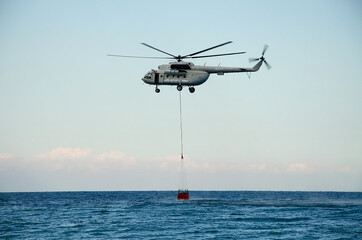 firefighter helicopter picks up water from the sea