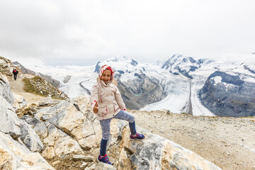 Children hiking in Alps mountains. Kids look at mountain in Austria. Spring family vacation. Outdoor fun and healthy activity.