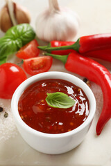 Spicy chili sauce with basil on table