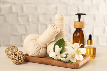 Beautiful jasmine flowers, herbal bags and skin care products on white wooden table