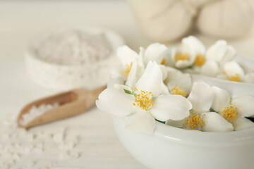Fototapeta na wymiar Mortar with beautiful jasmine flowers and pestle on white table, closeup. Space for text