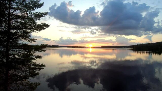 Time lapse footage of a calm summer evening in Lycksele, Sweden.Beautiful sunset with trees in the foreground.