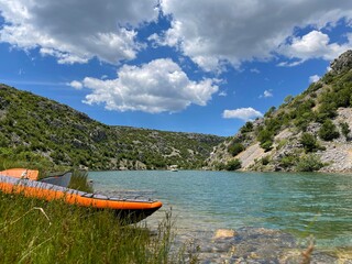 Orange Kayak on the Zrmanja river bank in Croatia. Karst landscape. Kayaking, canoeing, paddling. Dramatic sky.