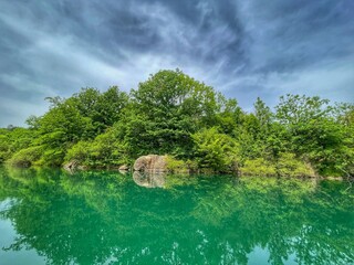 KOSINJ, CROATIA, June 2021 - Beautiful Lika river riverscape. Reflection in water and dramatic sky.