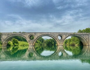 JUNE 2021, KOSINJ, CROATIA - historic stone bridge in Kosinj, Lika region. Reflection in the water. 