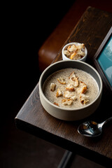 Button mushrooms cream soup with croutons on dark wooden table, top view