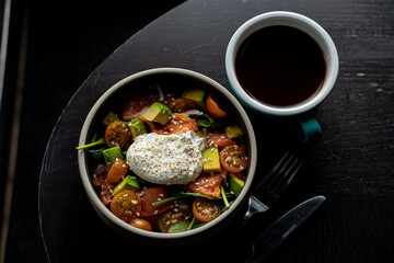 Top view of avocado salad with poached egg and smoked salmon as a light dinner in a fancy restaurant