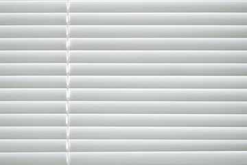 Obraz premium Frontal view of white office shutters made of metal. The strips are arranged horizontally, on the left there is a thread for opening the curtains. Texture, background and copy space.