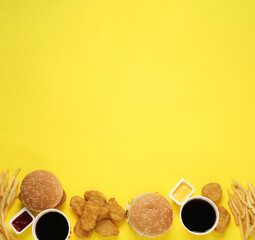 Different fast food on yellow background, flat lay. Space for text