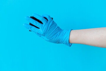 Female hand wear blue nitrile glove holding sponge and cleaning wall at home.