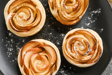Freshly baked apple roses on black plate, top view. Beautiful dessert