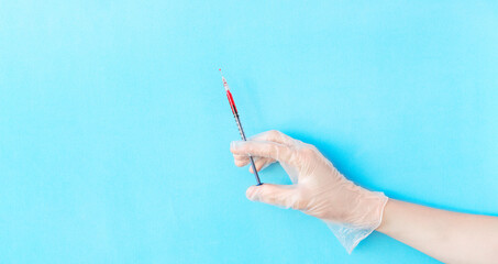 Banner with male hand in transparent vinyl disposable glove holding syringe above blue background...