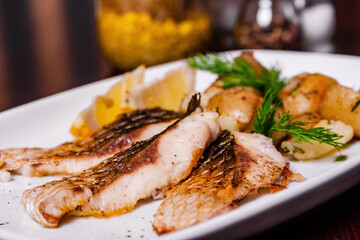 Carp steak with baked potatoes on a white plate
