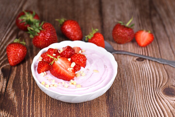 Strawberry yogurt bowl on wooden desk with berries