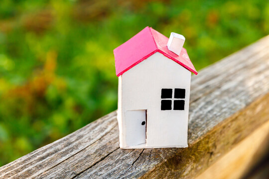 Miniature white toy model house in wooden background near green backdrop. Eco Village, abstract environmental background. Real estate mortgage property insurance dream home ecology concept.