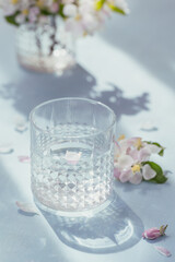 Glass of water on the table with blossoming apple tree branch in a glass