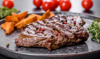 Delicious juicy fresh beef steak with spices and herbs on a dark concrete background