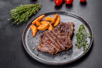 Delicious juicy fresh beef steak with spices and herbs on a dark concrete background
