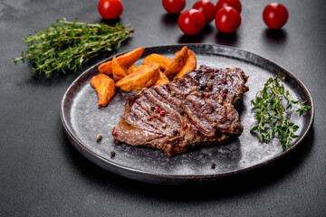 Delicious juicy fresh beef steak with spices and herbs on a dark concrete background