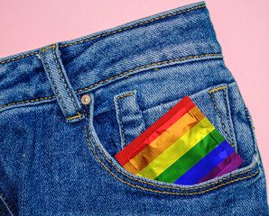condom with LGBT flag coloring in blue jeans pocket on pink background. safe love. symbol of freedom, peace and equality. Lesbian, gay, bisexual, transgender and gay. rainbow flag. LGBTQ