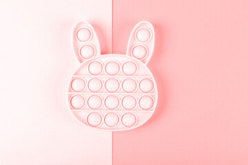 New silcone toy pop it in shape of bunny on the pink background. New sensory anti-stress toy for children and adult. Copy space. Flat lay. - obrazy, fototapety, plakaty