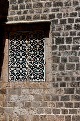 Wall of an old house and a window with a forged lattice