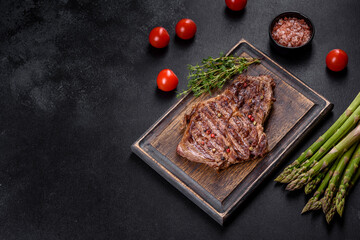 Delicious juicy fresh beef steak with spices and herbs on a dark concrete background