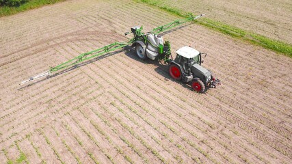 Traktor mit Feldspritze versprüht Pestizide auf Maisacker, Landwirtschaft aus der Vogelperspektive	