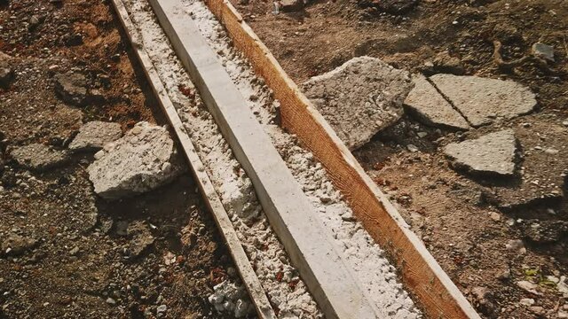 The new curbstone is mounted in a wooden formwork and is filled with fresh concrete.