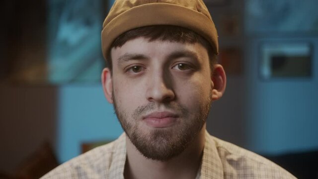 Portrait of young sad man with brown eyes, looking in camera with joyless, sorrowful view. Close-up of male face student having stubble beard.