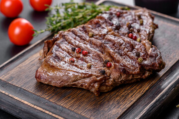 Delicious juicy fresh beef steak with spices and herbs on a dark concrete background