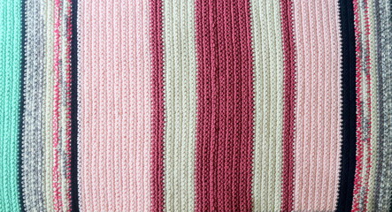 Knitted background, knitted wallpaper, knitted fabric, ricotted texture. Soft material. Handmade carpet closeup photo. Cozy background. Knitted details. 
