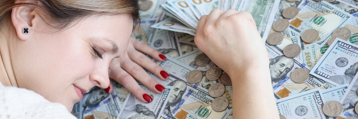 Woman with money in her hands sleeping on dollar bills