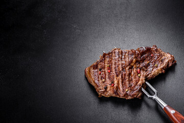 Delicious juicy fresh beef steak with spices and herbs on a dark concrete background