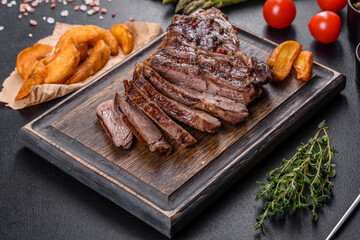 Delicious juicy fresh beef steak with spices and herbs on a dark concrete background
