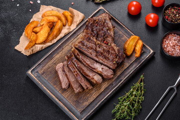 Delicious juicy fresh beef steak with spices and herbs on a dark concrete background