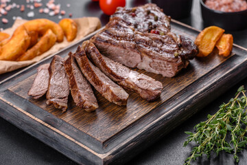 Delicious juicy fresh beef steak with spices and herbs on a dark concrete background
