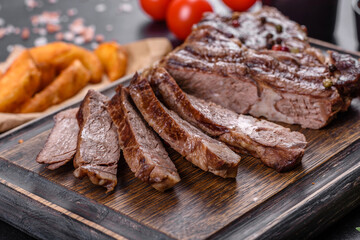 Delicious juicy fresh beef steak with spices and herbs on a dark concrete background