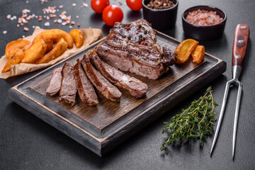 Delicious juicy fresh beef steak with spices and herbs on a dark concrete background