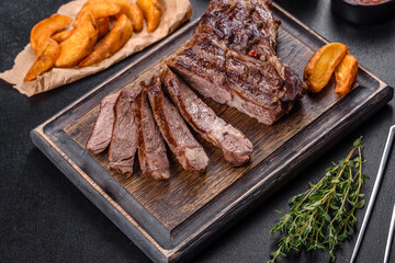 Delicious juicy fresh beef steak with spices and herbs on a dark concrete background