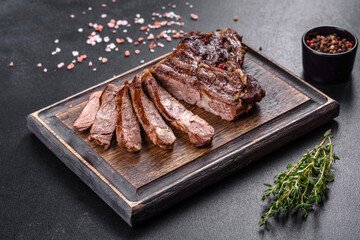 Delicious juicy fresh beef steak with spices and herbs on a dark concrete background