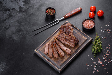 Delicious juicy fresh beef steak with spices and herbs on a dark concrete background