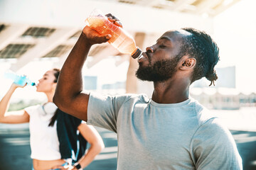 Fitness african athlete drinking energy drink outdoor - Fit people resting taking a break after...