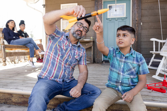 Father and son playing with toy rocket on porch