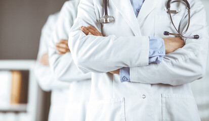 Group of modern doctors standing as a team with arms crossed in hospital office and ready to help patients. Medical help, insurance in health care, best disease treatment and medicine concept