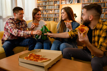 Friends eating pizza on a house party and having fun while drinking beer