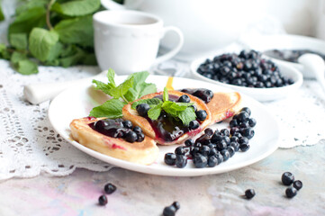 Breakfast with tea, pancakes, fresh blueberries and mint. Fried pancakes on a white plate